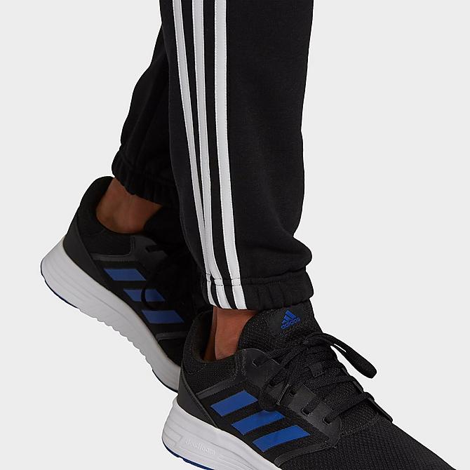 On Model 5 view of Men's adidas Essentials Fleece Tapered Elastic Cuff 3-Stripes Pants in Black Click to zoom
