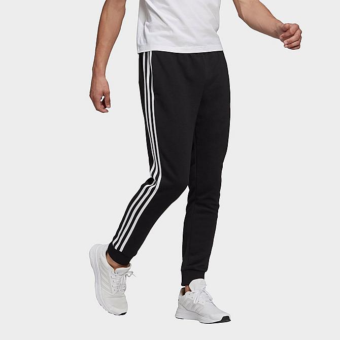 Front Three Quarter view of Men's adidas Essentials French Terry Tapered Cuff 3-Stripes Pants in Black/White Click to zoom