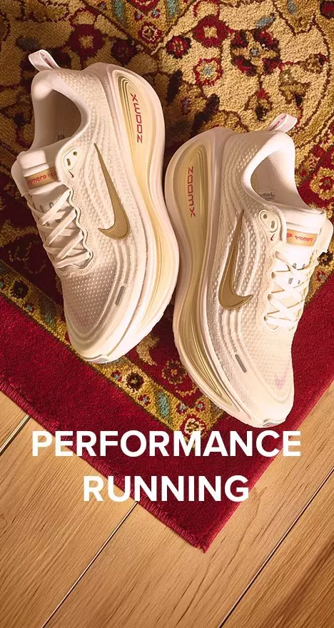 Pair of women's cream and gold Nike ZoomX running shoes on a ornate rug, featuring text overlay reading "Performance Running."